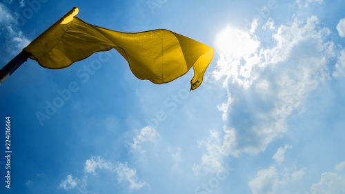 yellow flag on a background of the dark blue sky with clouds.