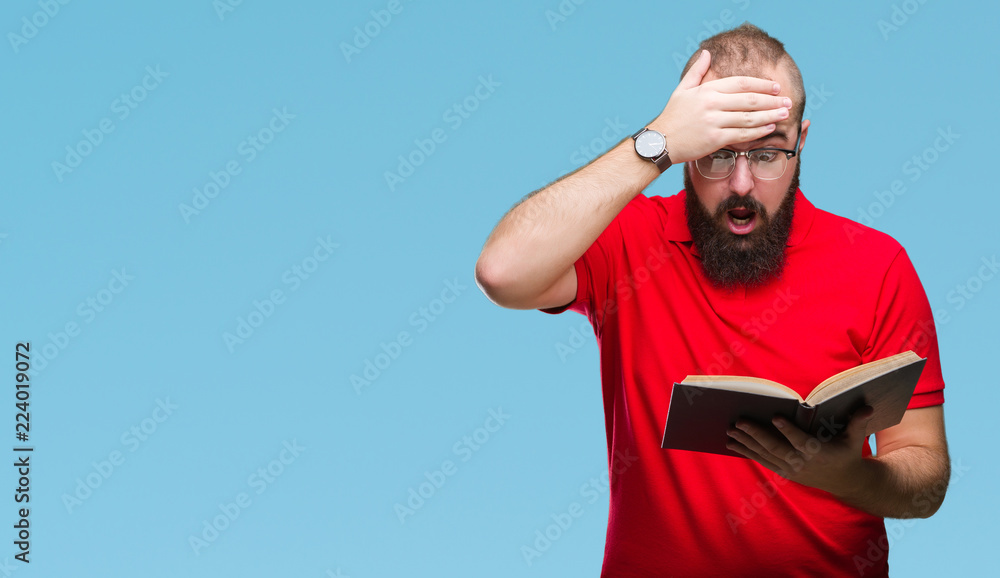 Fototapeta premium Young hipster man wearing glasses and reading a book over isolated background stressed with hand on head, shocked with shame and surprise face, angry and frustrated. Fear and upset for mistake.