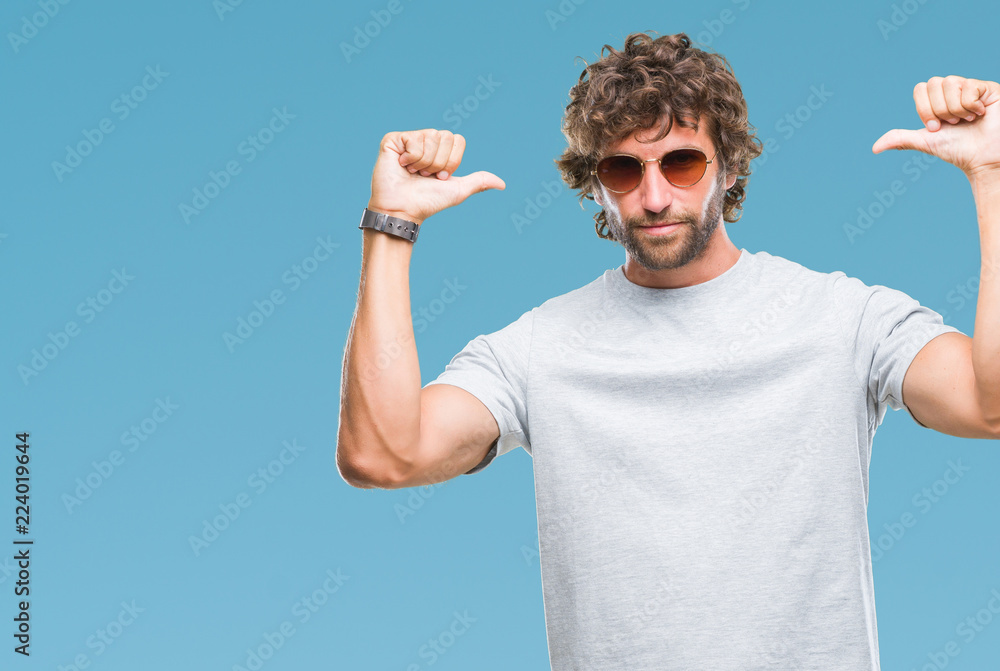 Naklejka premium Handsome hispanic model man wearing sunglasses over isolated background looking confident with smile on face, pointing oneself with fingers proud and happy.
