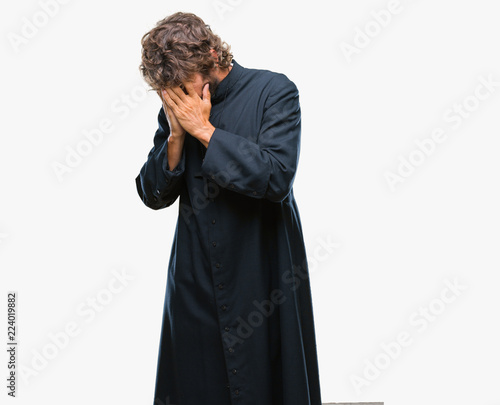 Handsome hispanic catholic priest man over isolated background with sad expression covering face with hands while crying. Depression concept.