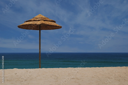 Praia com abrigo de sol em palhas, guarda sol em madeira e palha numa praia de ambiente tropical