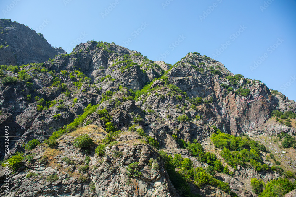 Majestic landscape of the mountains and forest in Caucasus at summer. Dramatic sky with clouds.