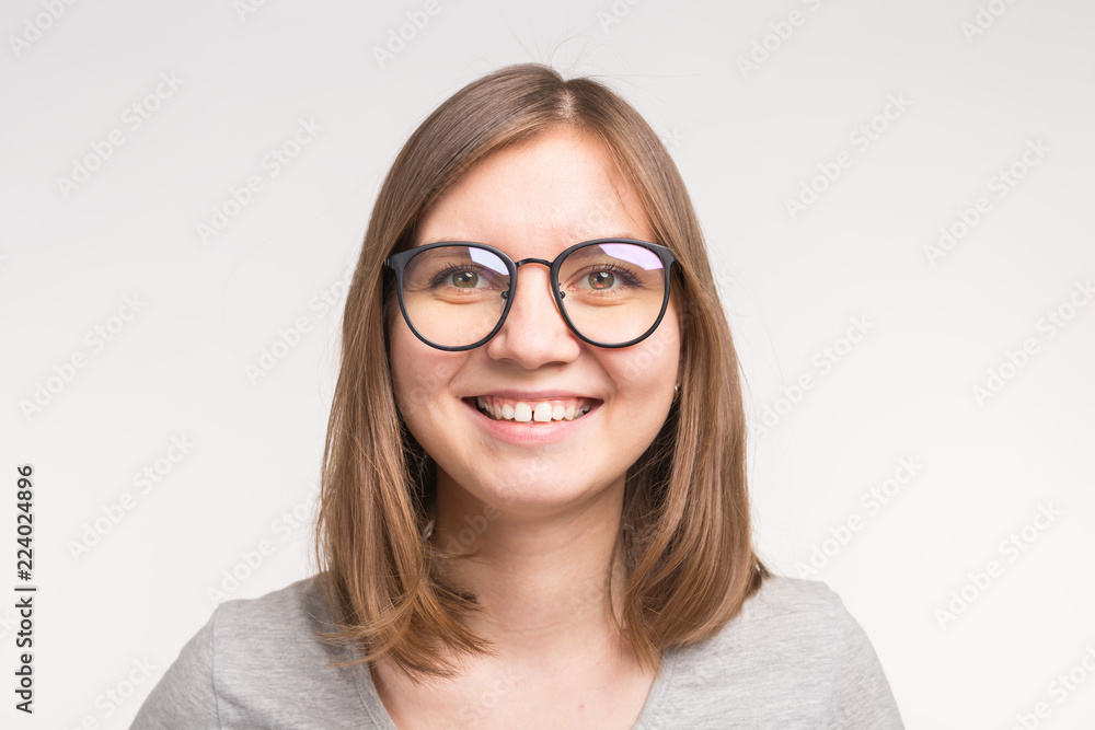 Close-up of young beautiful woman in glasses over white background.