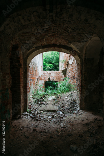 Inside ruined, abandoned ancient brick aged castle building overgrown with grass and plants