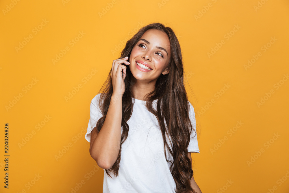 Portrait of caucasian woman 20s with long hair smiling and talking on mobile phone, isolated over yellow background Portrait of caucasian woman 20s with long hair smiling and talking on mobile phone, isolated over yellow background