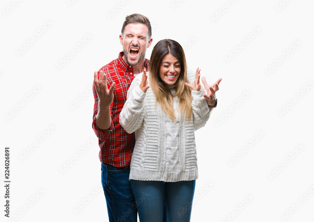 Young couple in love wearing winter sweater over isolated background celebrating mad and crazy for success with arms raised and closed eyes screaming excited. Winner concept Young couple in love wearing winter sweater over isolated background celebrating mad and crazy for success with arms raised and closed eyes screaming excited. Winner concept