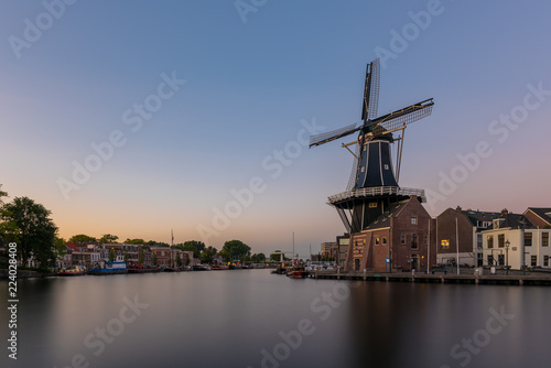 Dutch windmill, in the town of Haarlem, at sunset. The water is smooth, due to a long shutter speed - room for copy