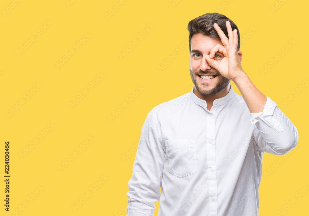 Young handsome man over isolated background doing ok gesture with hand smiling, eye looking through fingers with happy face. Young handsome man over isolated background doing ok gesture with hand smiling, eye looking through fingers with happy face.
