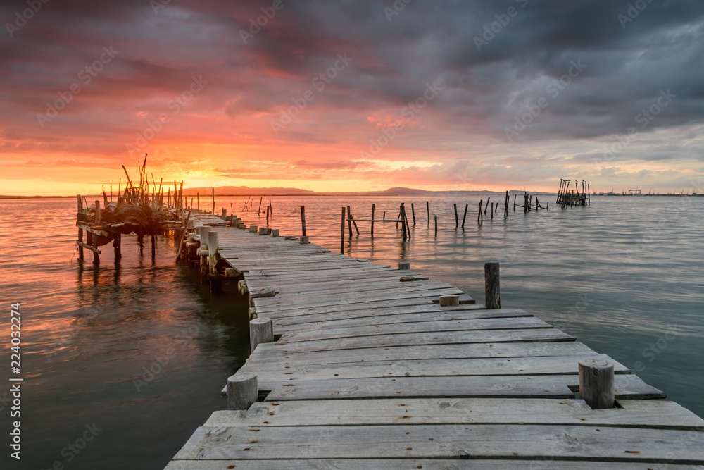 Sunset landscape of artisanal fishing boats in the old wooden pier. Carrasqueira is a tourist destination for visitors to the coast of Alentejo near Lisbon.