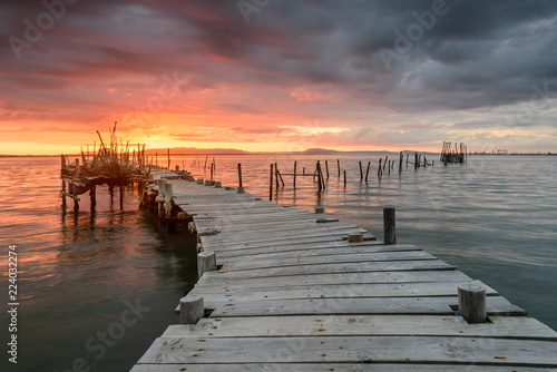 Sunset landscape of artisanal fishing boats in the old wooden pier. Carrasqueira is a tourist destination for visitors to the coast of Alentejo near Lisbon.