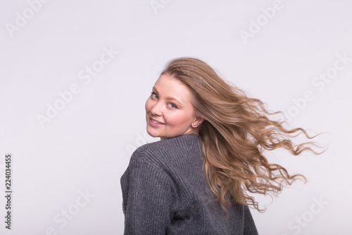Smiling woman with flying hair on white background with copy space