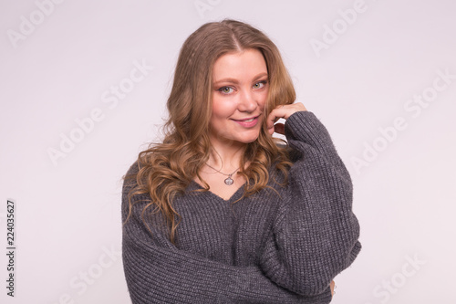 Close up portrait of caucasian tender woman with curly hair wearing gray cardigan on white background