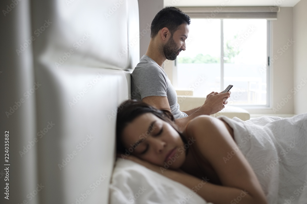 Couple In Bed With Cheating Man Texting On Smartphone Couple In Bed With Cheating Man Texting On Smartphone