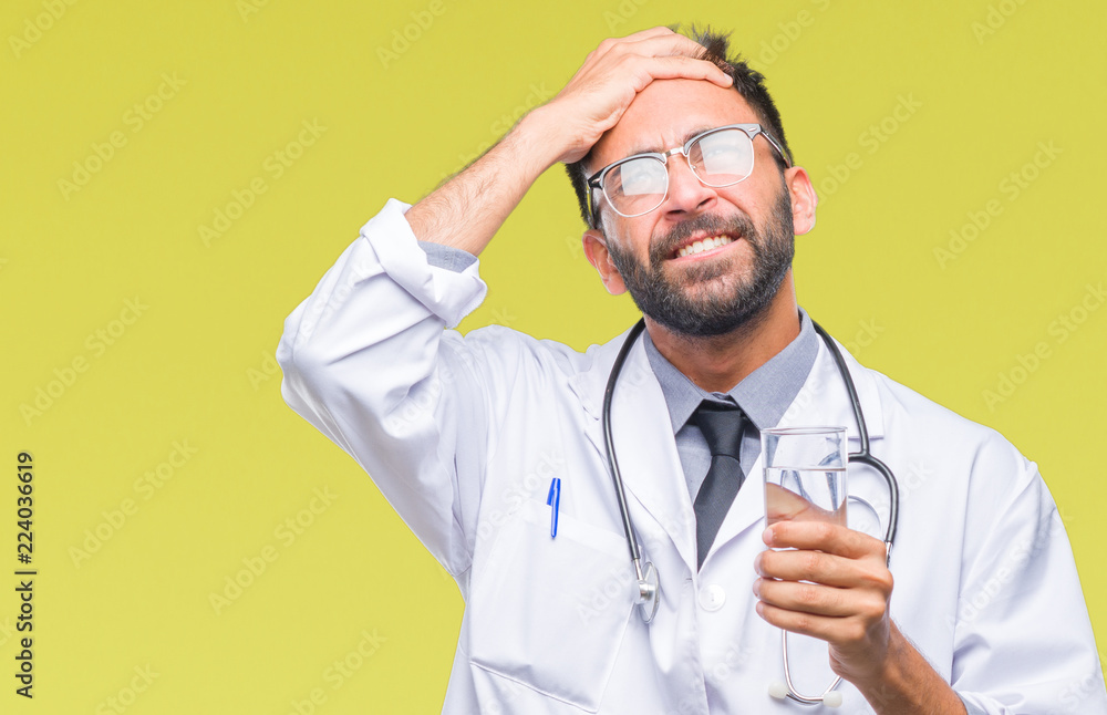 Adult hispanic doctor man drinking glass of water over isolated background stressed with hand on head, shocked with shame and surprise face, angry and frustrated. Fear and upset for mistake. Adult hispanic doctor man drinking glass of water over isolated background stressed with hand on head, shocked with shame and surprise face, angry and frustrated. Fear and upset for mistake.
