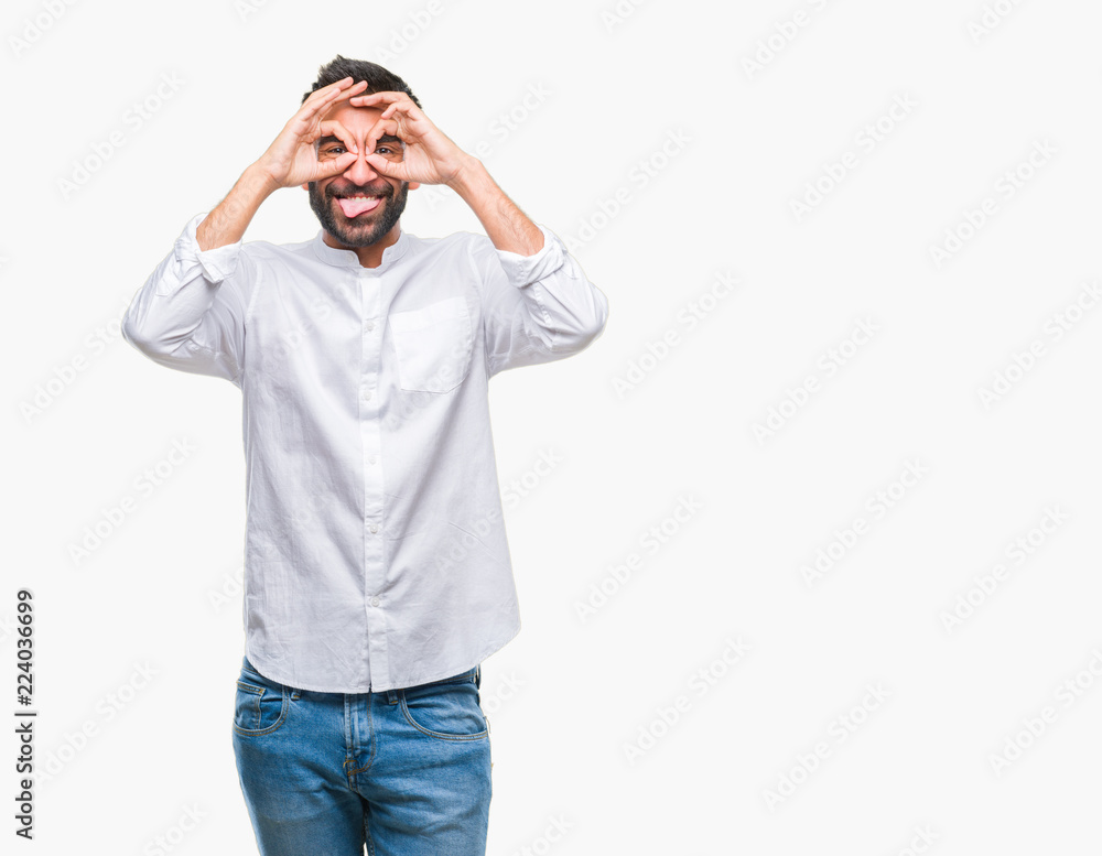 Adult hispanic man over isolated background doing ok gesture like binoculars sticking tongue out, eyes looking through fingers. Crazy expression. Adult hispanic man over isolated background doing ok gesture like binoculars sticking tongue out, eyes looking through fingers. Crazy expression.