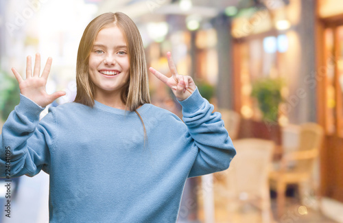 Fototapeta Naklejka Na Ścianę i Meble -  Young beautiful girl wearing winter sweater over isolated background showing and pointing up with fingers number seven while smiling confident and happy.