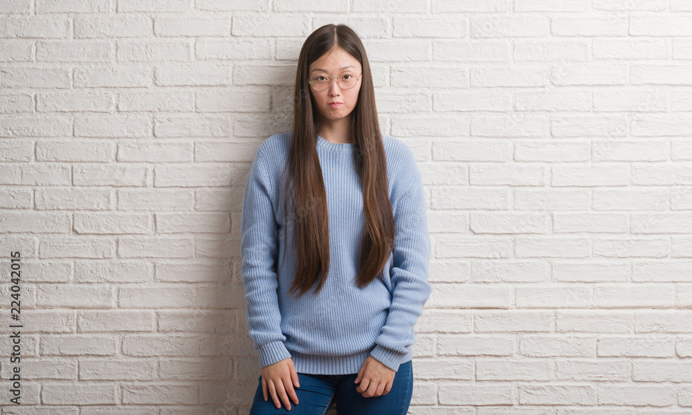 Young Chinise woman over white brick wall depressed and worry for distress, crying angry and afraid. Sad expression. Young Chinise woman over white brick wall depressed and worry for distress, crying angry and afraid. Sad expression.