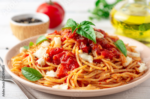 Fotografia, Obraz Spaghetti pasta with tomato sauce, mozzarella cheese and fresh basil in plate on white wooden background