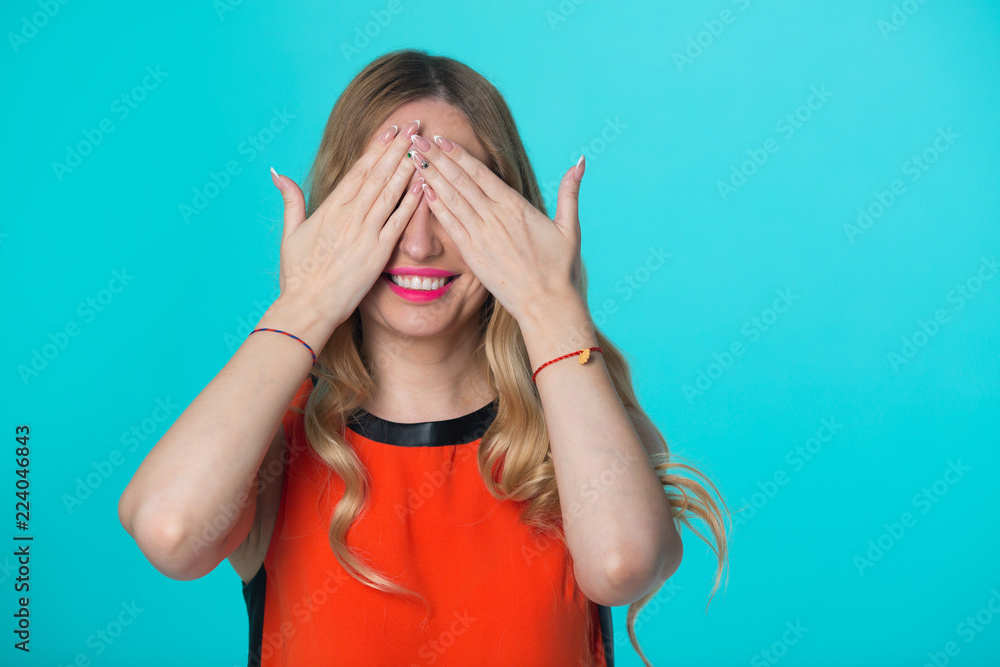beautiful young girl with her hair on blue background closes her eyes with her hands beautiful young girl with her hair on blue background closes her eyes with her hands