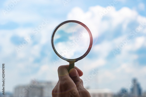 hands holding glass magnify against blue sky background. Business Explore, Searching, Discovery and Vision concepts