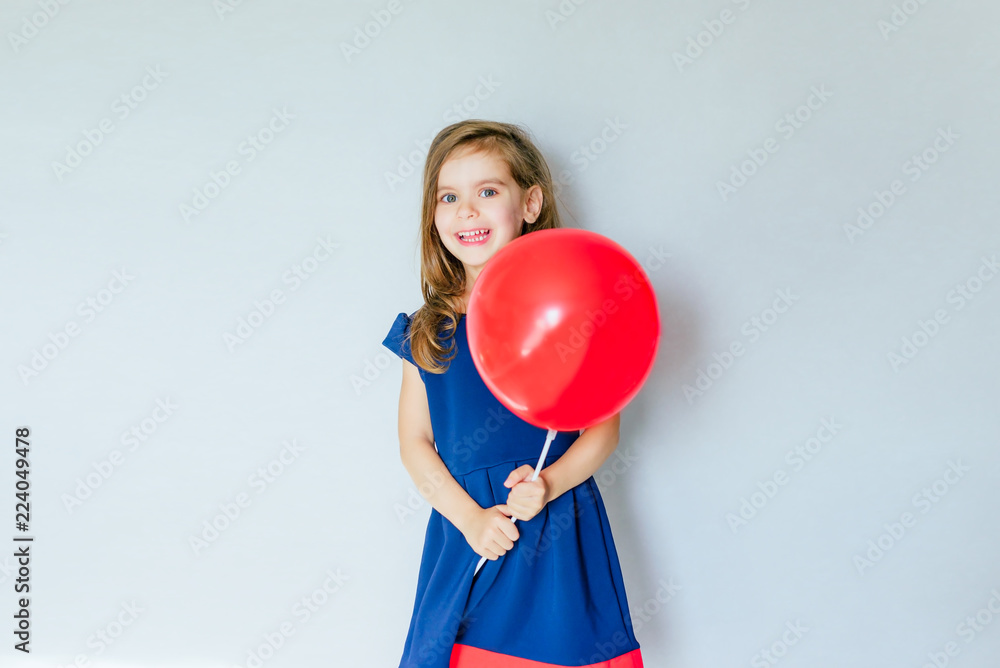 Happy funny girl with red balloon near empty grey concrete walls. The concept of the celebration. The beginning of sales. black Friday. Happy funny girl with red balloon near empty grey concrete walls. The concept of the celebration. The beginning of sales. black Friday.