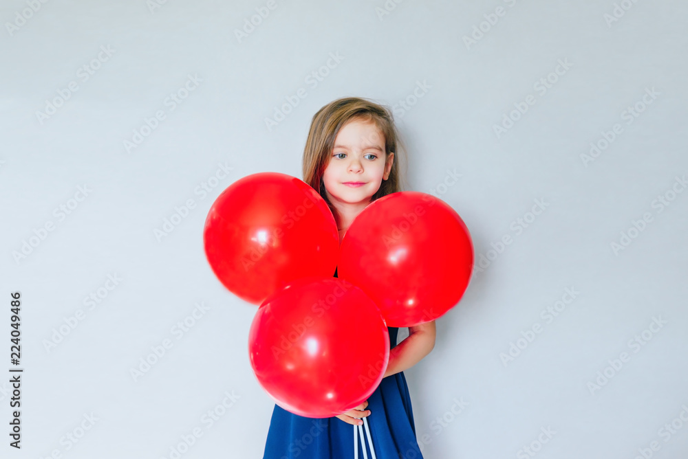 Happy funny girl with red balloon near empty grey concrete walls. The concept of the celebration. The beginning of sales. black Friday. Happy funny girl with red balloon near empty grey concrete walls. The concept of the celebration. The beginning of sales. black Friday.