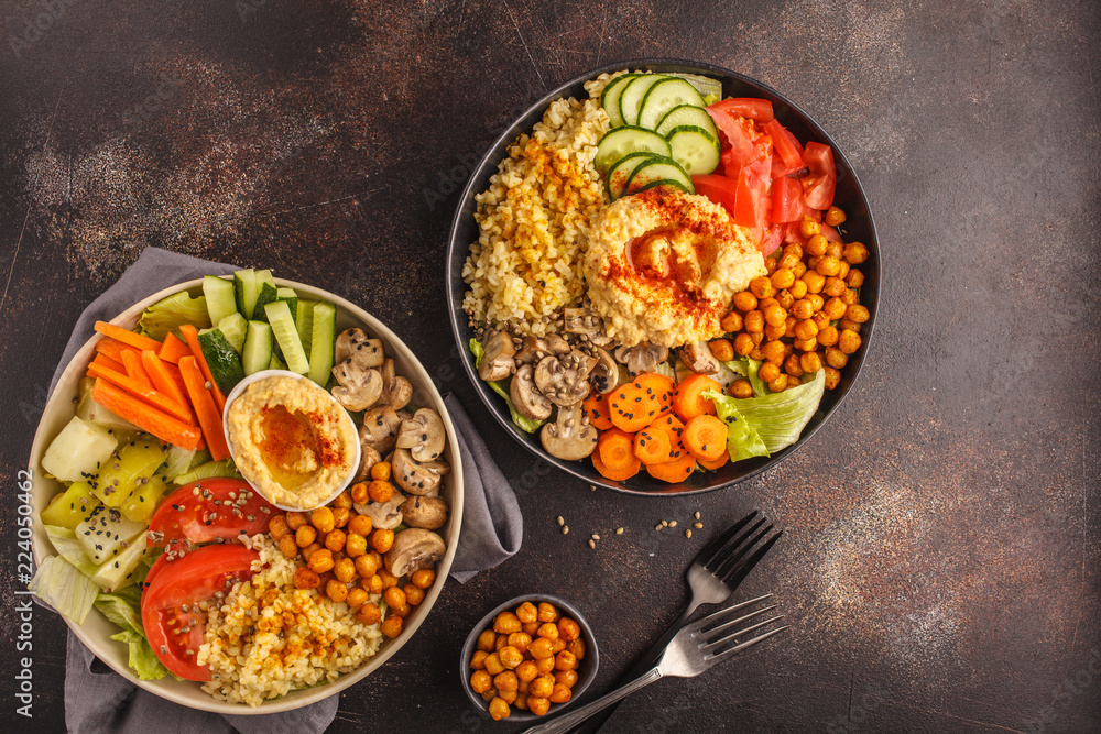 Buddha bowls with vegetables, mushrooms, bulgur, hummus and baked chickpeas. Dark background, top view.
