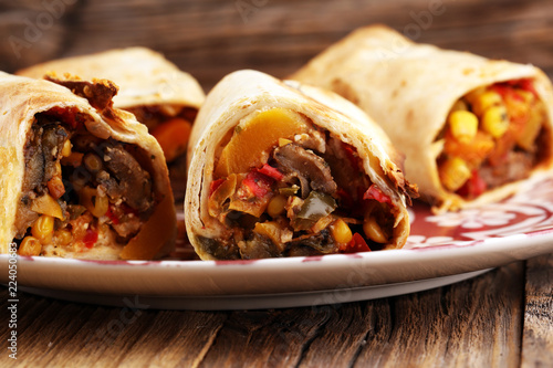 Burritos wraps with beef and vegetables on wooden background. Beef burrito, mexican food