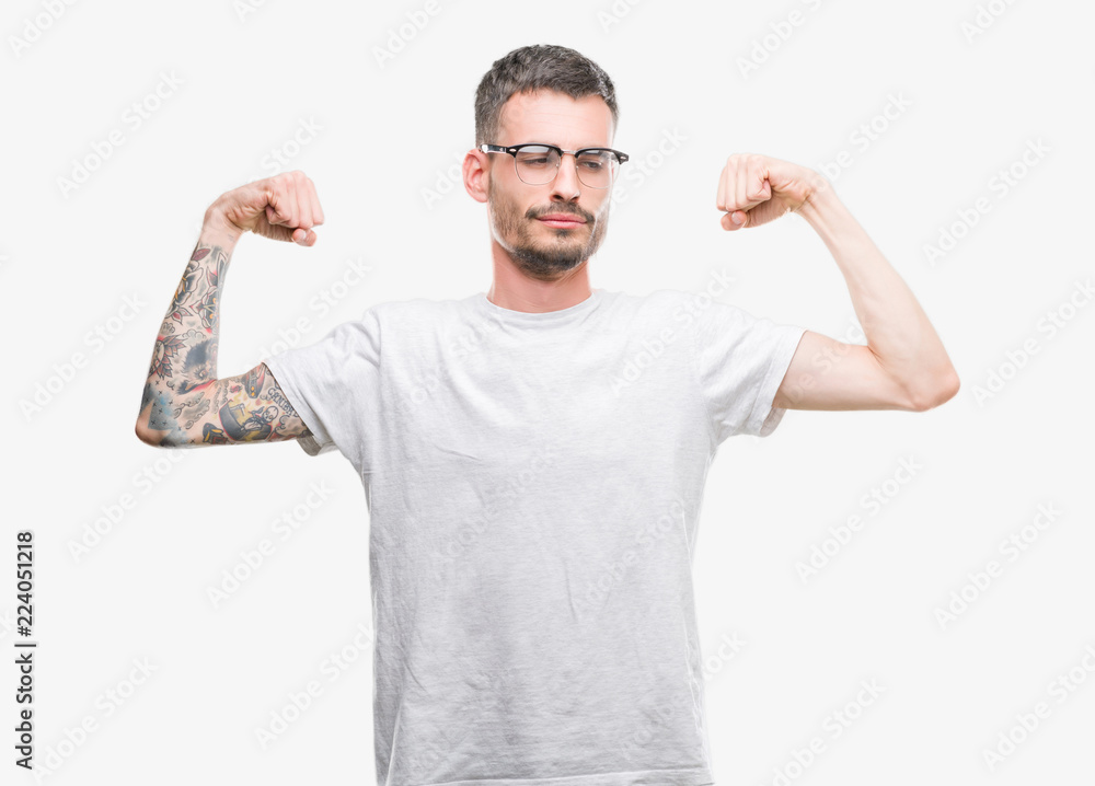 Young tattooed adult man showing arms muscles smiling proud. Fitness concept.