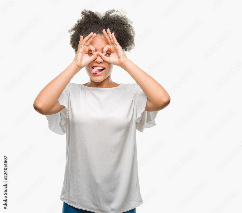 Young afro american woman over isolated background doing ok gesture like binoculars sticking tongue out, eyes looking through fingers. Crazy expression. Young afro american woman over isolated background doing ok gesture like binoculars sticking tongue out, eyes looking through fingers. Crazy expression.