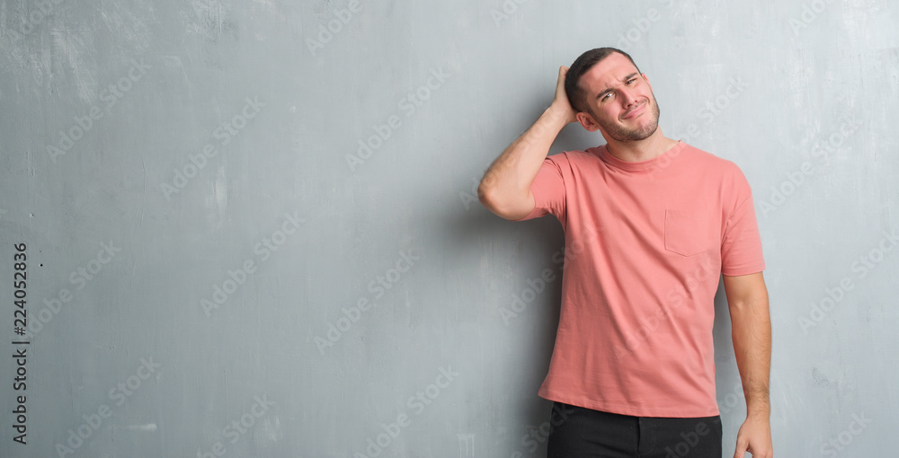 Young caucasian man over grey grunge wall confuse and wonder about question. Uncertain with doubt, thinking with hand on head. Pensive concept. Young caucasian man over grey grunge wall confuse and wonder about question. Uncertain with doubt, thinking with hand on head. Pensive concept.