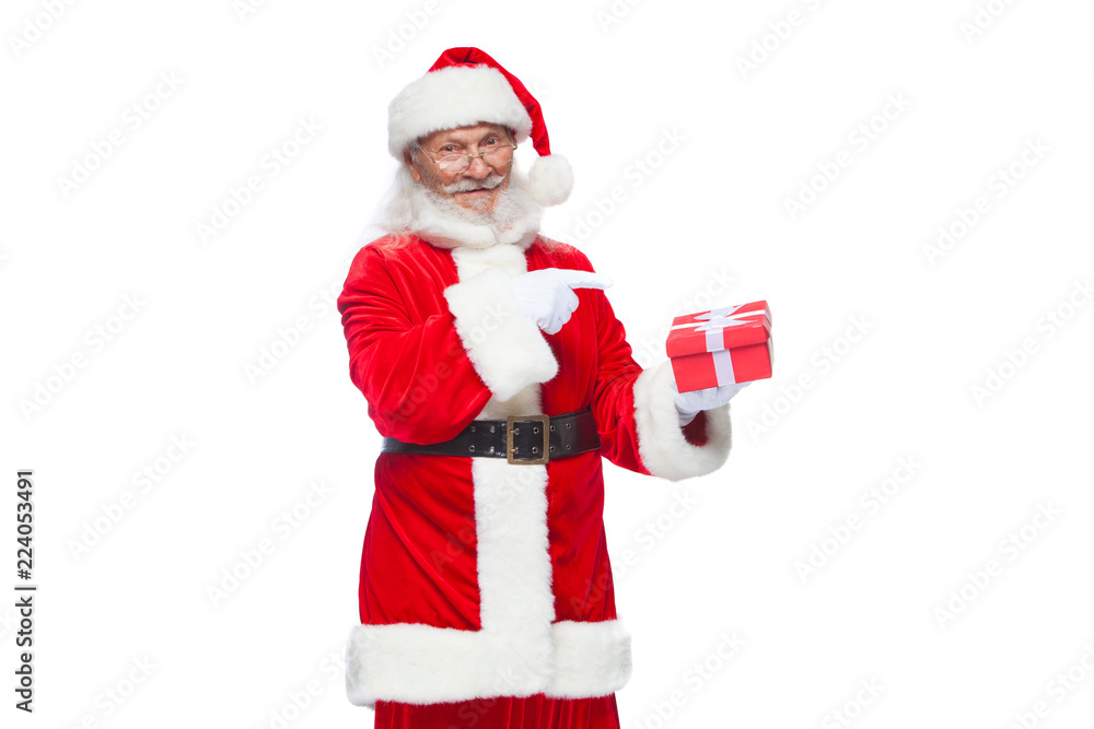 Christmas. Smiling Santa Claus in white gloves is holding a gift red box with a bow. Pointing at the gift. Isolated on white background. Christmas. Smiling Santa Claus in white gloves is holding a gift red box with a bow. Pointing at the gift. Isolated on white background.