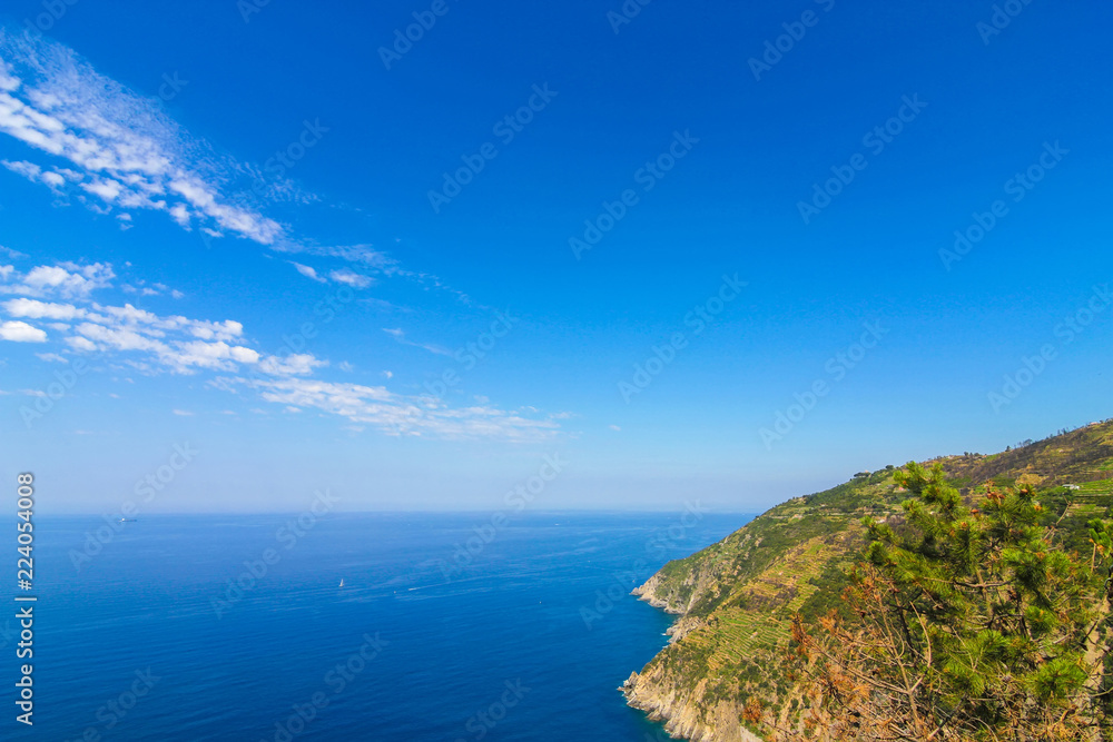View over the blue Mediterranean Sea and the mountains of Cinque Terre, Italy on a sunny day with blue sky.