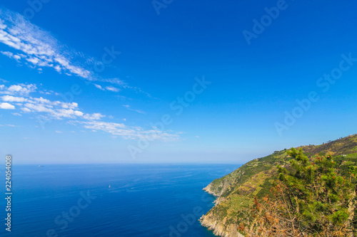 View over the blue Mediterranean Sea and the mountains of Cinque Terre, Italy on a sunny day with blue sky. © Spectral-Design