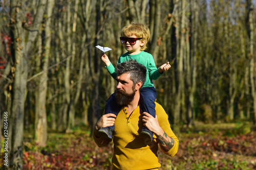 Father and child play together in park. Father and child launch paper plane outdoor. Lets fly away