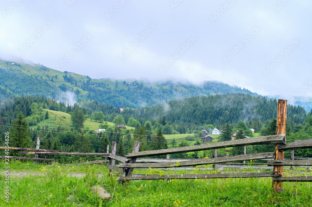 wooden fence in the background of the village in the mountains of foggy. Ukraine Carpathians