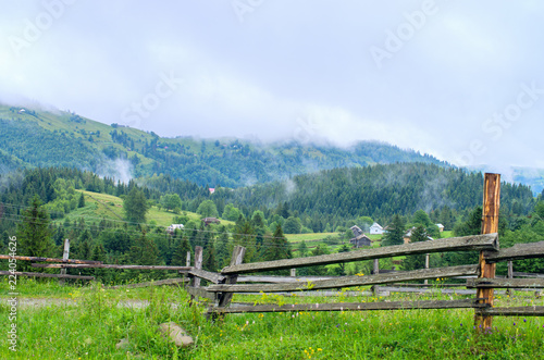 wooden fence in the background of the village in the mountains of foggy. Ukraine Carpathians