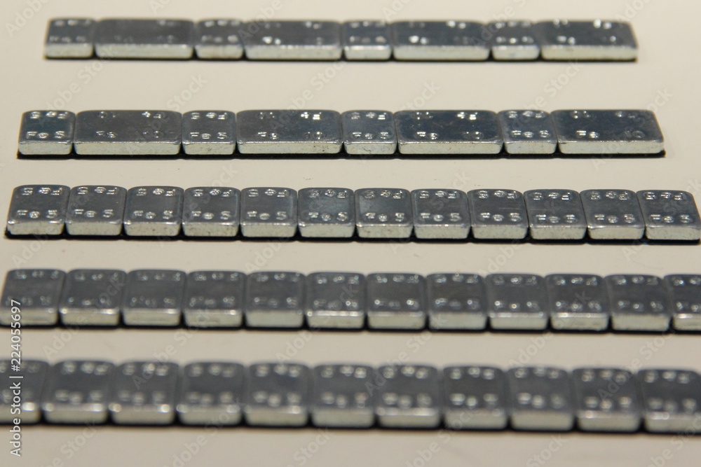 Equipment and supplies for car service and tire balancing — new stainless self-adhesive balance weights (counterweights) for motor vehicles on white background Equipment and supplies for car service and tire balancing — new stainless self-adhesive balance weights (counterweights) for motor vehicles on white background