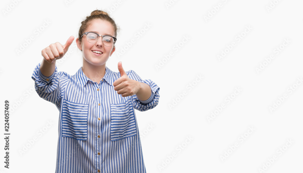 Young blonde business woman approving doing positive gesture with hand, thumbs up smiling and happy for success. Looking at the camera, winner gesture. Young blonde business woman approving doing positive gesture with hand, thumbs up smiling and happy for success. Looking at the camera, winner gesture.
