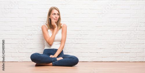 Beautiful young woman sitting on the floor at home touching mouth with hand with painful expression because of toothache or dental illness on teeth. Dentist concept.