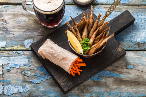 Beer snack deep fried small fishes with carrots sticks photo