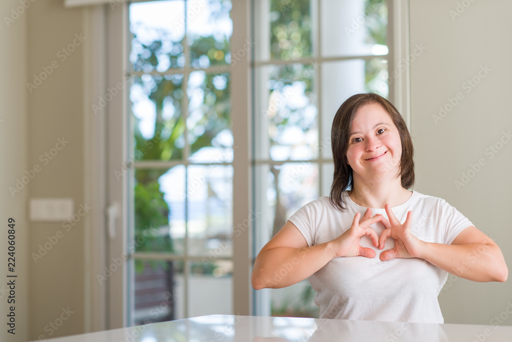 Down syndrome woman at home smiling in love showing heart symbol and shape with hands. Romantic concept. Down syndrome woman at home smiling in love showing heart symbol and shape with hands. Romantic concept.