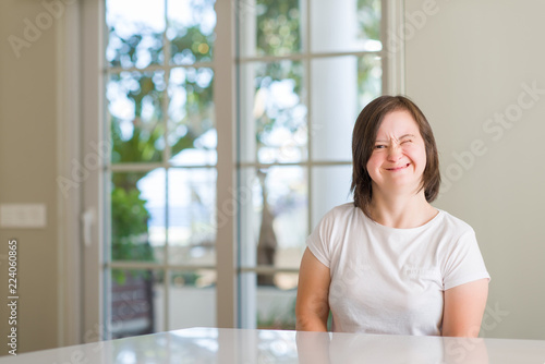 Down syndrome woman at home winking looking at the camera with sexy expression, cheerful and happy face.