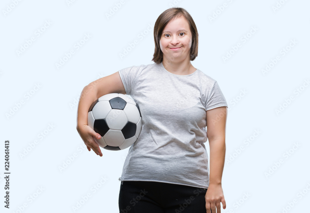Young adult woman with down syndrome holding soccer football ball over isolated background with a happy face standing and smiling with a confident smile showing teeth