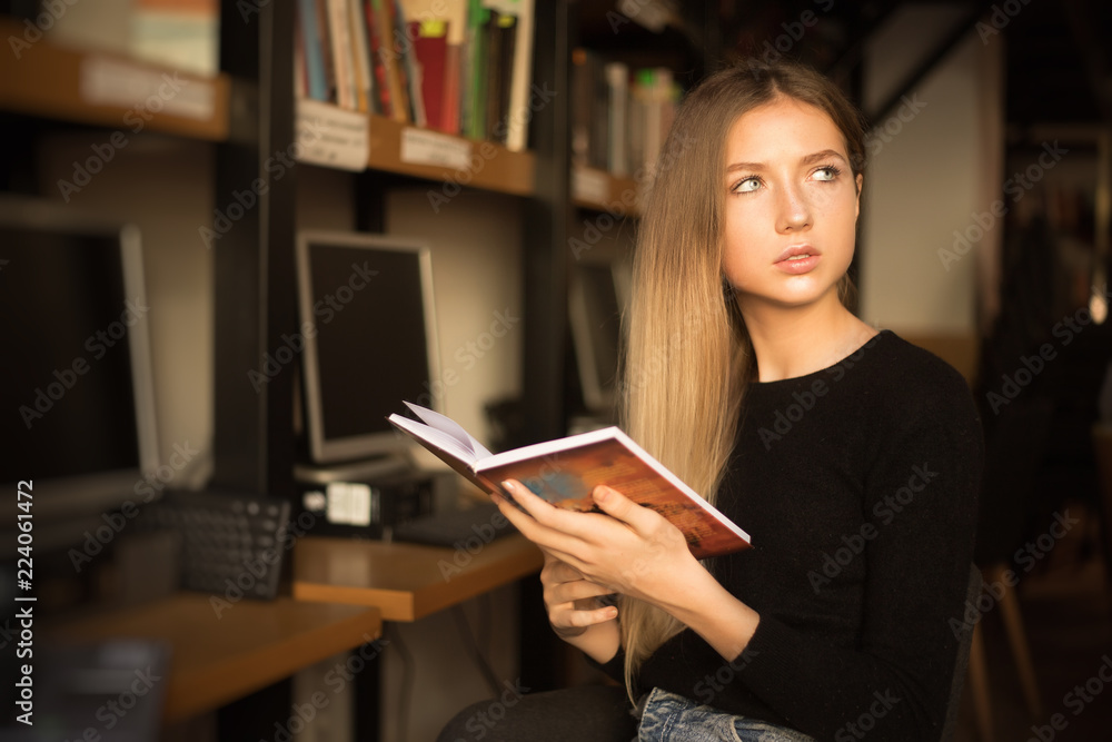 Serious young teenage girl student sitting in library reading book. Looking aside doing homework. Serious young teenage girl student sitting in library reading book. Looking aside doing homework.
