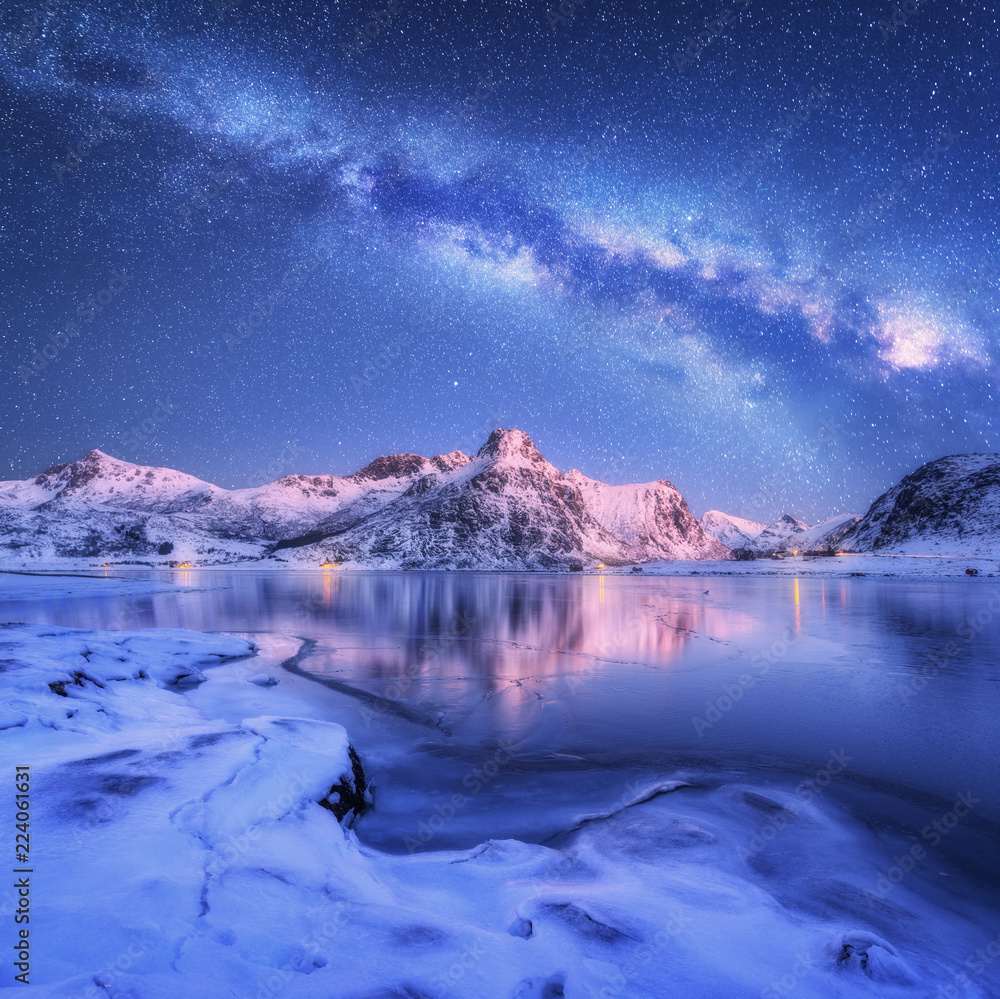 Milky Way above frozen sea coast and snow covered mountains in winter