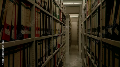 Slow camera movement between two archive shelves filled with folders. The image can be used for the integration of archive texts in films and reports. Thanks to the 50 frames it can be slowed down.
