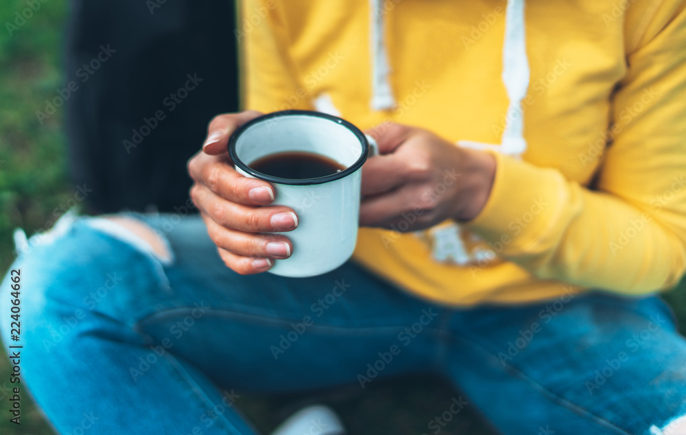 Close up girl holding in hands cup of hot tea on green grass in outdoors nature park, beautiful woman hipster enjoy drinking cup of coffee, lifestyle relax recreation meditation concept Close up girl holding in hands cup of hot tea on green grass in outdoors nature park, beautiful woman hipster enjoy drinking cup of coffee, lifestyle relax recreation meditation concept