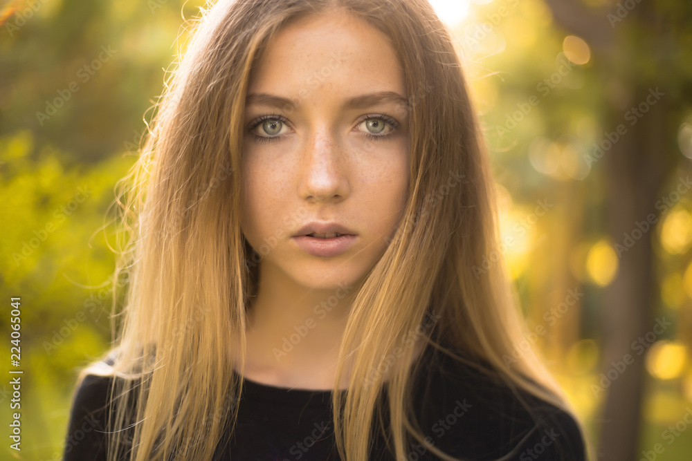 Beautiful serious concentrated girl student posing in the park outdoors on grass looking camera. Beautiful serious concentrated girl student posing in the park outdoors on grass looking camera.