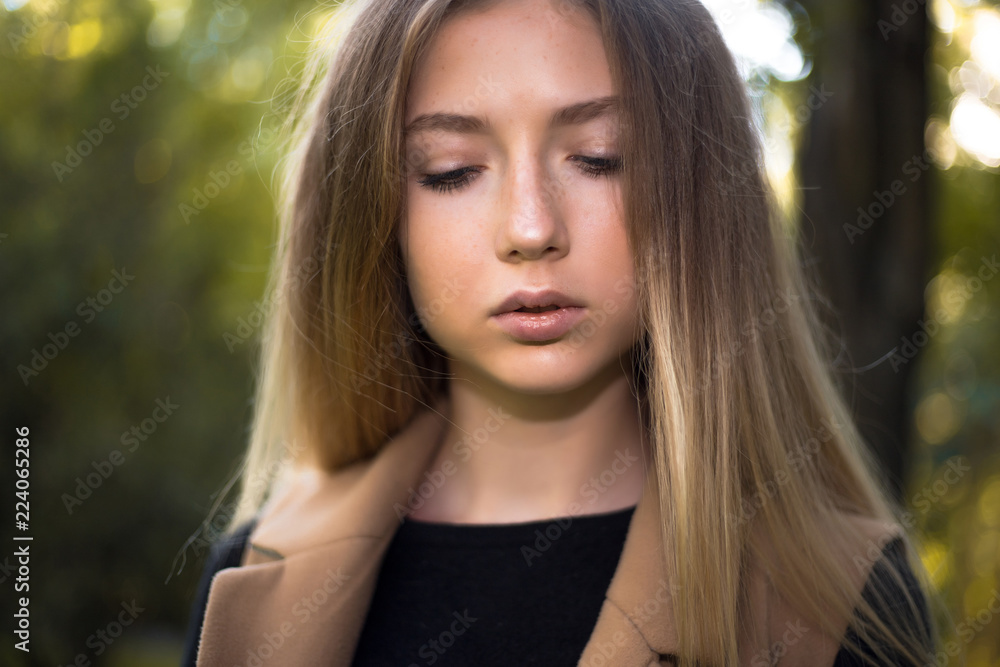 Beautiful serious concentrated girl student posing in the park outdoors on grass looking aside. Beautiful serious concentrated girl student posing in the park outdoors on grass looking aside.